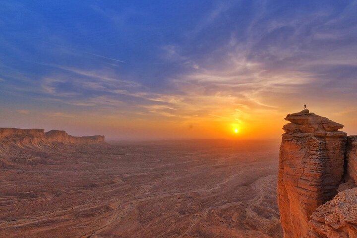Edge of the World in Riyadh during sunset with glowing sky and stars appearing above desert cliffs.
