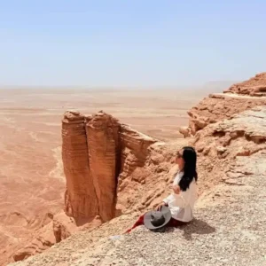 Woman enjoying the view at Edge of the World, showcasing desert safari etiquette Saudi Arabia