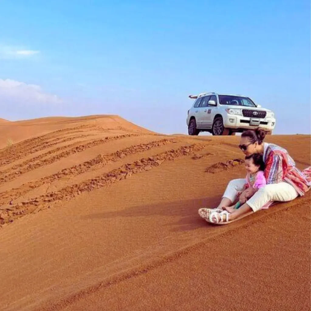 Family enjoying a desert safari Riyadh with kids, riding camels, sandboarding, and exploring golden dunes at sunset.