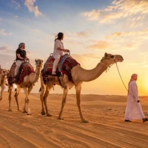 "The Ultimate Guide to Camel Ride Riyadh – tourists enjoying camel rides across golden desert dunes with sunrise views"